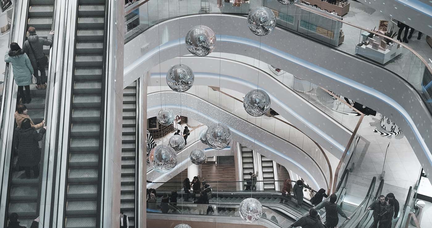 A group of people going up the escalator at an indoor mall.